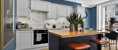 A modern kitchen with white cabinets, a wooden island, and bar stools.