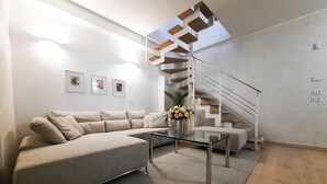 A modern living room with a sectional sofa, a glass coffee table, and a spiral staircase. - Il Coccodrillo By Case al Lago (Sirmione)