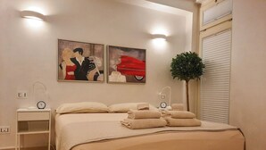 A bedroom with a bed, two wall-mounted light fixtures, a clock, a small shelf, and a potted plant. - Il Coccodrillo By Case al Lago (Sirmione)