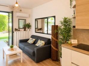 A modern living room with a sofa, a coffee table, and a kitchen area with a sink and cabinets.