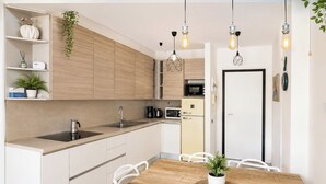 Una cocina moderna con armarios de madera, un lavamanos y una zona de comedor con una mesa y sillas de madera.