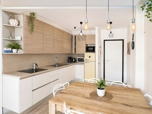 A modern kitchen with wooden cabinets, a sink, and a dining area with a wooden table and chairs.