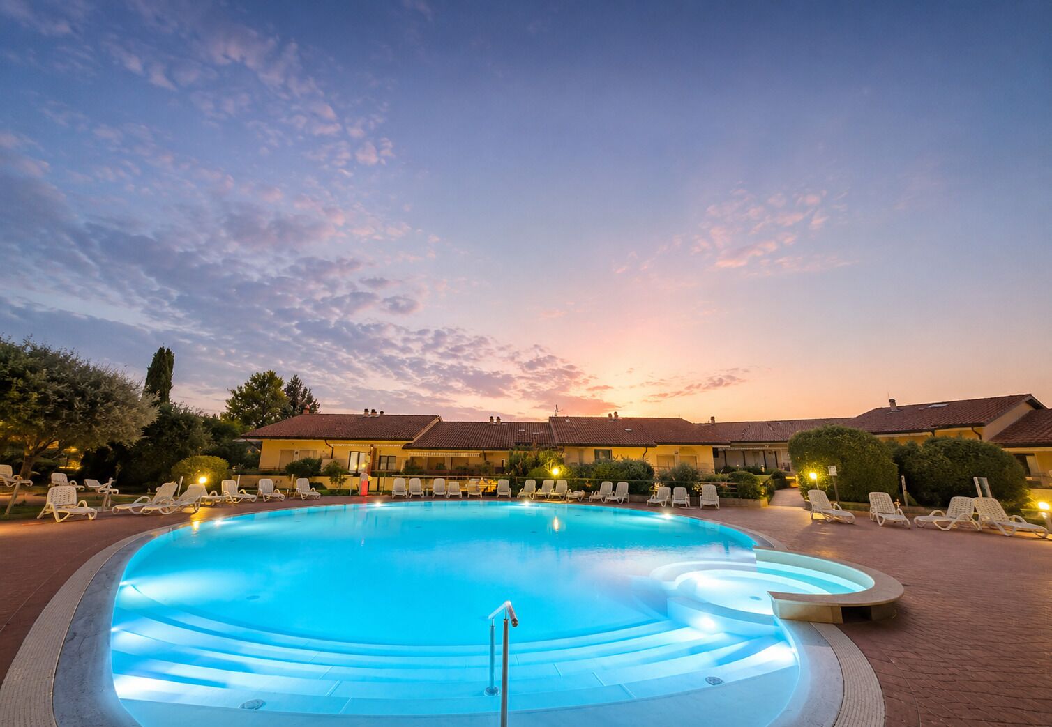 A swimming pool with lounge chairs and a building in the background.