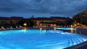 Una piscina con sillas de descanso y un edificio al fondo.