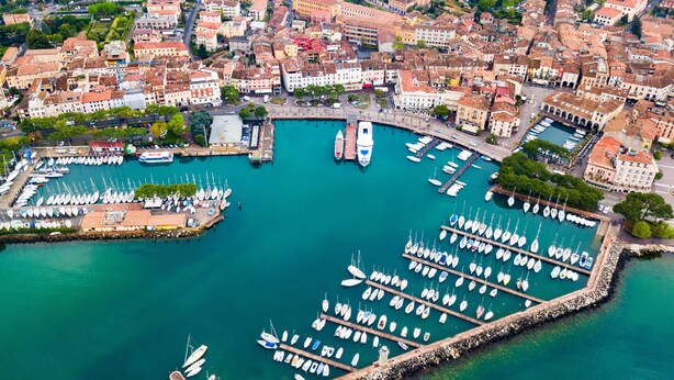 Vista aérea de un puerto deportivo con numerosas embarcaciones amarradas, rodeado de una zona urbana densamente poblada con edificios históricos.