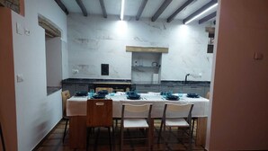 Uma sala de jantar com uma parede de mármore, piso ladrilhado e uma mesa posta para quatro pessoas.