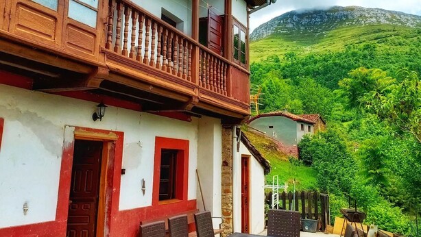 Um edifício tradicional com varanda, área de estar ao ar livre e vista para uma encosta verdejante.