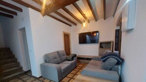 Sala de estar com dois sofás, uma televisão e uma escada.