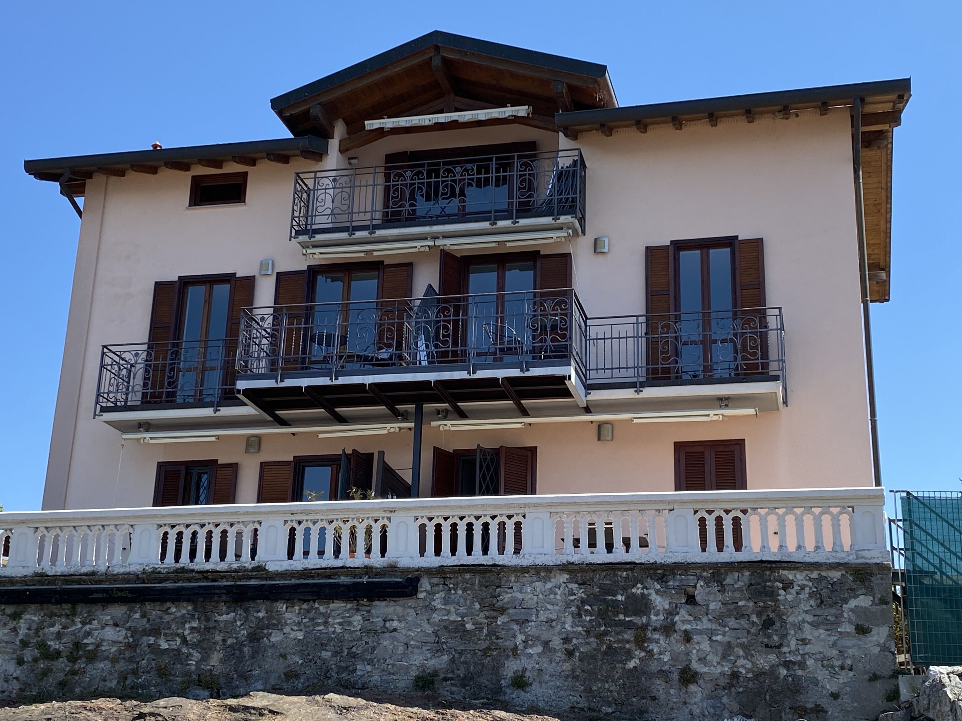 A multi-story building with balconies, a stone base, and a white railing.