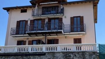 A multi-story building with balconies, a stone base, and a white railing.