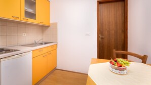 A kitchen with yellow cabinets, a white countertop, and a wooden door.