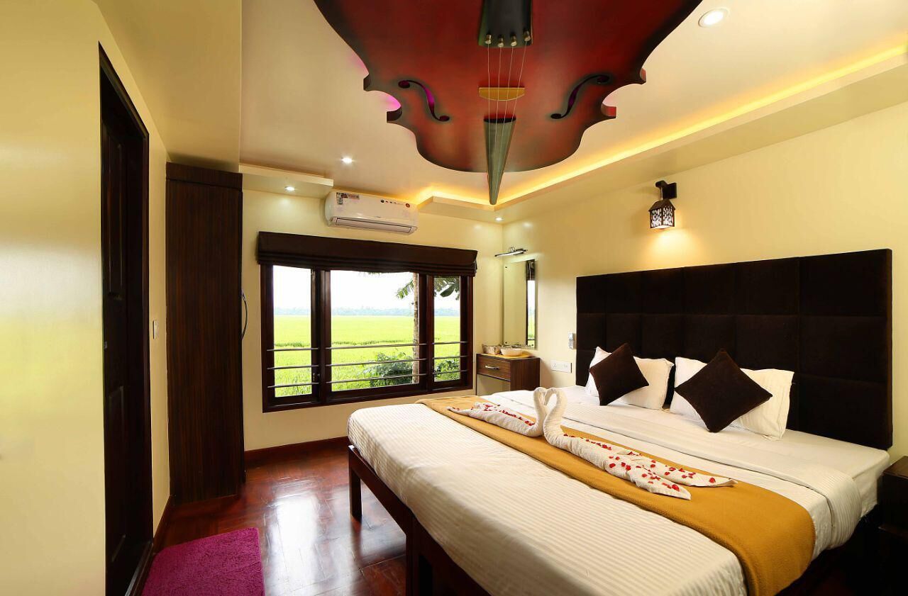 A hotel room with a large bed, a window with a view of the countryside, and a ceiling with a unique design.