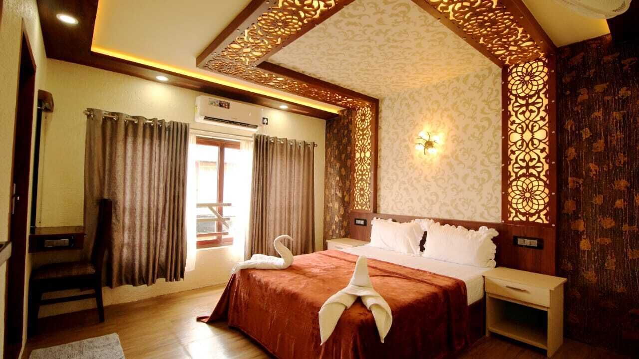 Habitación de hotel con cama, mesita de noche, silla, cortinas y un panel decorativo en la pared.
