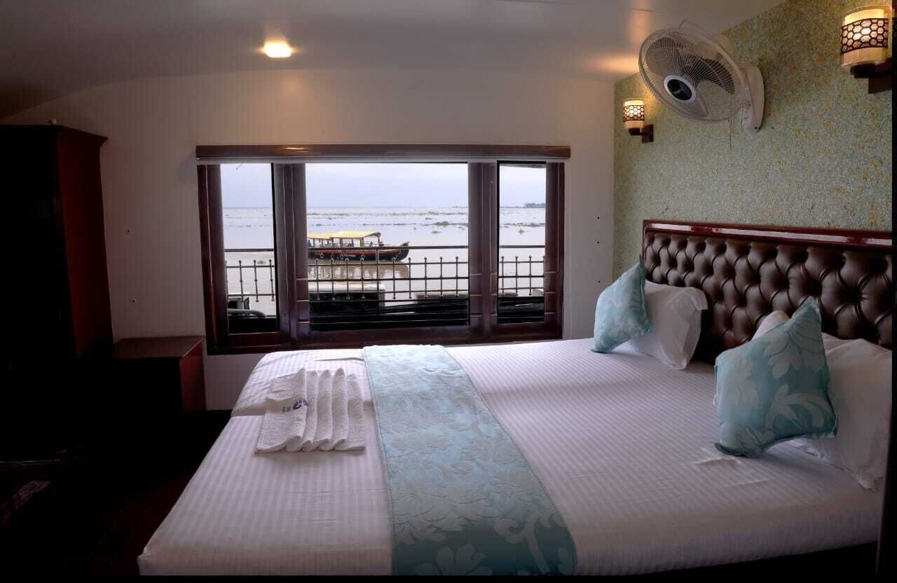 Una habitación de hotel con una cama grande, vistas al mar, un balcón y un ventilador.