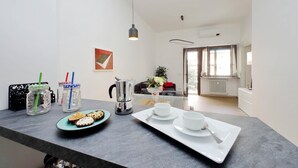 A modern kitchen with a dining area, featuring a coffee machine, jars with straws, a plate with pastries, and a tray with cups and a spoon. - 4bnb - Cozy Albornoz Flat (Rome)