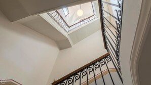 Eine Treppe mit aufwendiger schwarzer Metallgeländer und einem Oberlicht darüber.