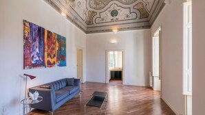 Ein geräumiges Wohnzimmer mit einem modernen Sofa, einem farbenfrohen abstrakten Gemälde und einem schlichten Couchtisch.