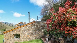 A stone house with a sloped roof, a small window, and a stone wall. - Monkleigh Mill (Bideford)