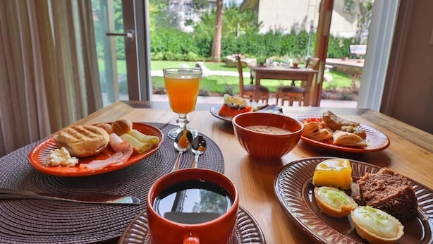 Una mesa de desayuno con platos de comida, un vaso de jugo de naranja y una taza de café.