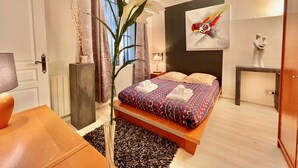 A modern bedroom with a bed, bedside tables, a vase with flowers, and a painting on the wall. - Center of Paris - Aladdin's house (Paris)