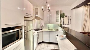 A compact kitchen with modern appliances, a built-in oven, a sink, and a dining area with a bench. - Center of Paris - Aladdin's house (Paris)
