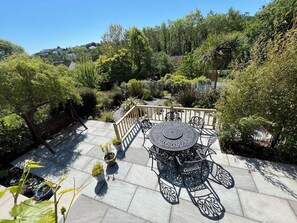 Relax in a serene outdoor space surrounded by lush greenery and potted plants, with a round table and six chairs.