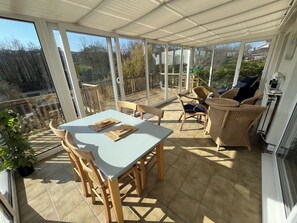 Relax on the shaded patio with a view of the surrounding greenery and wooden deck.
