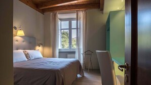 Une chambre à coucher avec un lit, une fenêtre avec des rideaux, une chaise et une porte.