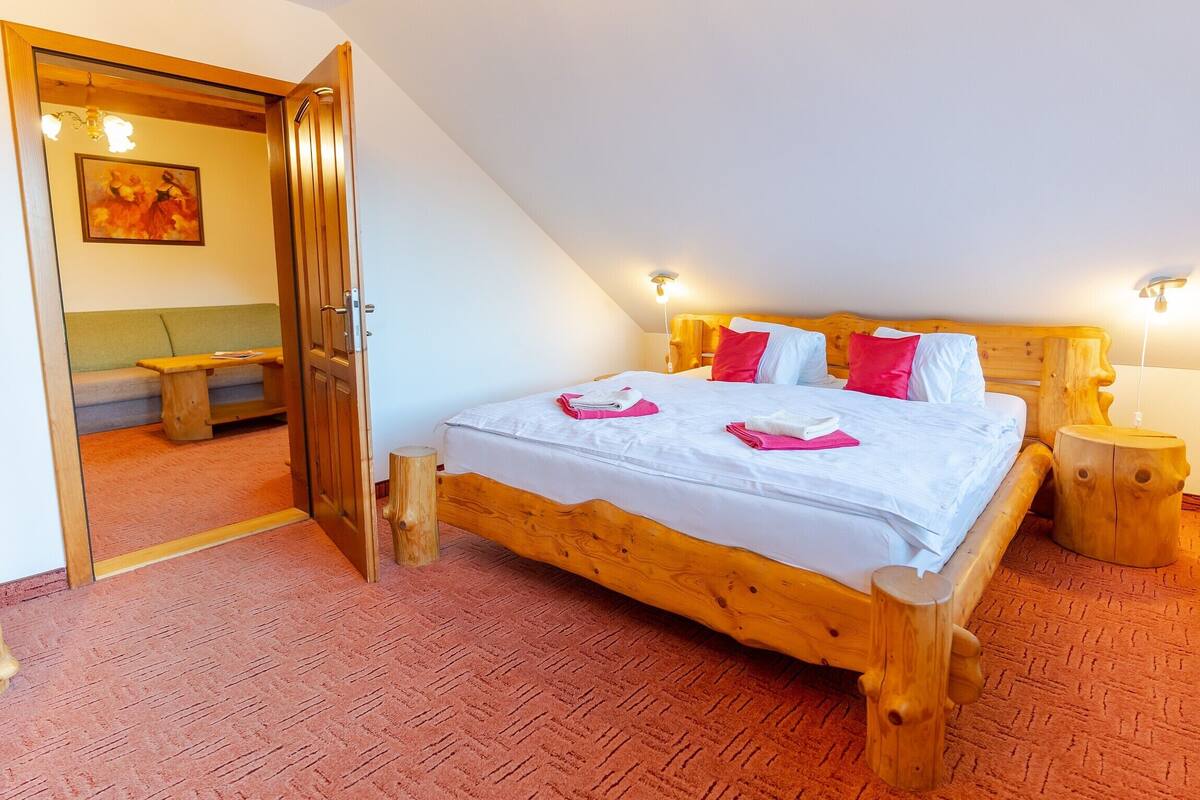 Ein Schlafzimmer mit einem hölzernen Bett, einer Bank, einem Gemälde und einem Holzschemel.