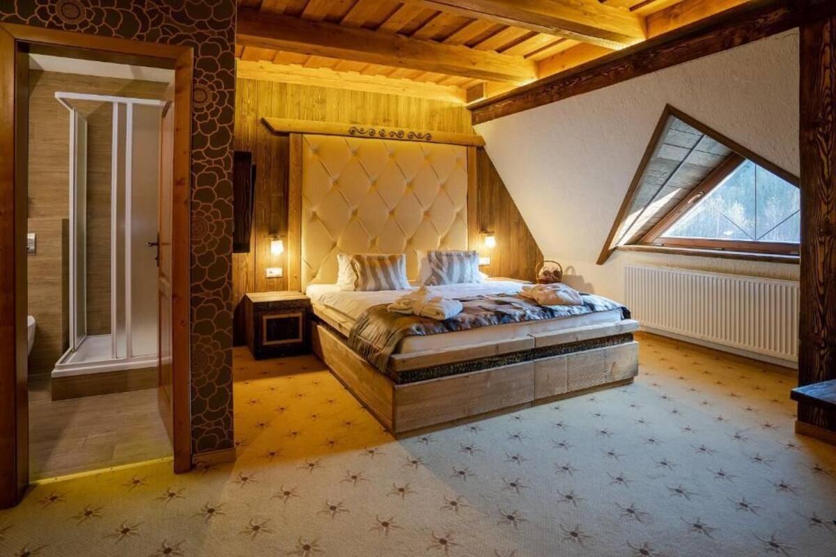 Ein Schlafzimmer mit einem großen Bett, einer Holzbalkendecke, einer Steinwand und einem Oberlicht.