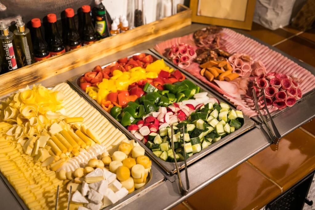 Un buffet proposant une variété de plats, notamment des légumes, des fromages et des viandes.