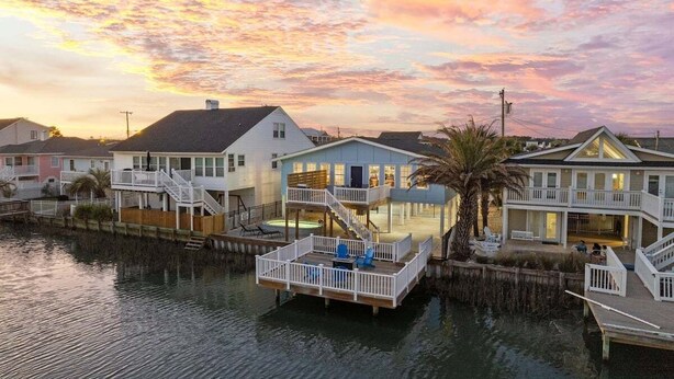 A waterfront property with multiple houses connected by docks, featuring balconies and outdoor seating areas.