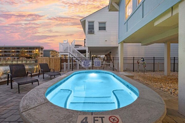 A swimming pool with a 4 FT depth marker, lounge chairs, and a waterfront view. - Charlie's Beach Retreat | Fun 4BR w/ Heated Pool (North Myrtle Beach)