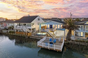 A waterfront property with a dock, multiple houses, and a clear view of the water. - Charlie's Beach Retreat | Fun 4BR w/ Heated Pool (North Myrtle Beach)