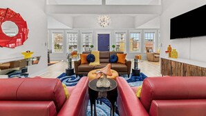 A spacious living room with a sofa, a coffee table, and a TV mounted on the wall.