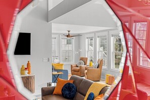 A modern living room with a brown sofa, a blue coffee table, and a ceiling fan.
