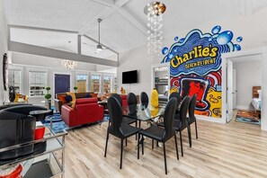 A spacious living area with a dining table, red sofa, and a wall mural.