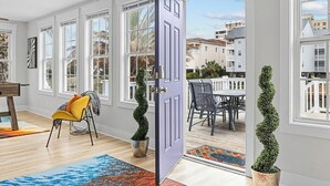 A modern interior with large windows, a dining area, and a door leading outside.