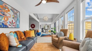 A modern living room with a sofa, armchair, and a large abstract painting.