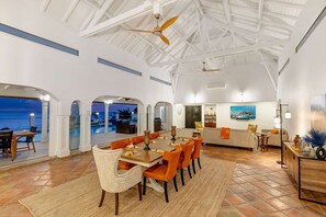 A spacious interior with a dining area, kitchen, and a view of the ocean.