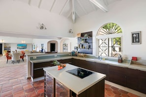A spacious kitchen with a central island, dark wooden cabinets, and a large window with a view of greenery.