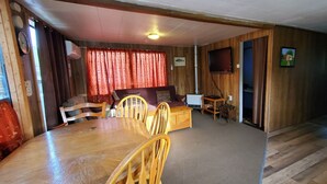 Una habitación acogedora con una mesa de comedor de madera, sillas, un sofá y un televisor.