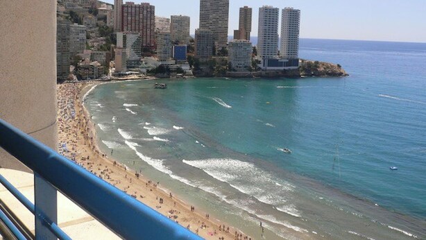 Paisatge urbà costaner amb una platja, edificis alts i un cel serè.