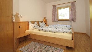 Un dormitorio pequeño y acogedor con una cama individual, una ventana con cortinas y un armario de madera.