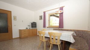 Un comedor con una mesa, sillas, televisor y sofá.