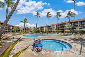 A hotel with multiple swimming pools, palm trees, and a clear blue sky.