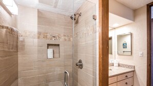 Un baño moderno con cabina de ducha de vidrio, tocador con espejo y perchero para toallas.