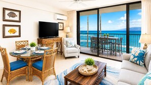 Habitación de hotel con comedor, sofá, balcón y vista al océano, además de un televisor.