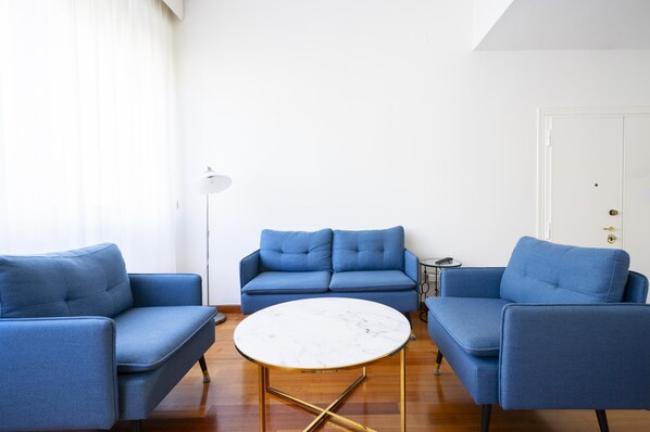 A living room with a blue sofa set, a round coffee table, and a floor lamp. - Sprone Apartment in Firenze (Florence)