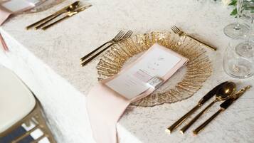 Una mesa puesta con cubiertos dorados, una servilleta rosa y un menú.